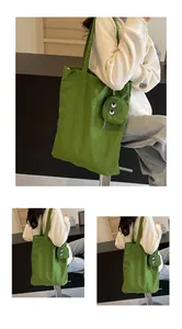 Close-up of green canvas tote bag with monster eye coin purse and embroidered details