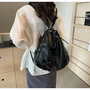 Detailed view of black hobo bag with wrinkle texture and bow knot on female model