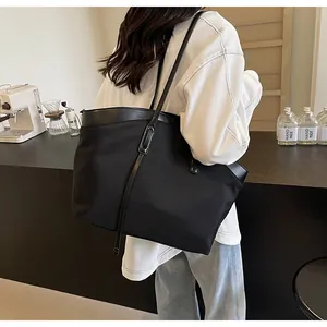 Side view of large black nylon tote bag worn by a model in a cafe setting