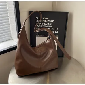 Détail d'un sac Hobo marron montrant la texture fine du cuir et le design en croissant