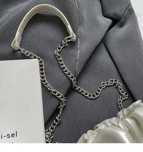 Détail de la bandoulière chaîne argentée et de la protection en cuir du sac seau crème