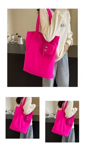 Detail of vibrant hot pink canvas tote bag featuring embroidered monster eyes and coin pouch