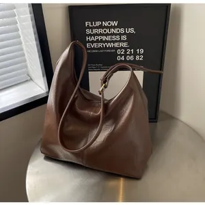 Détail d'un sac cabas marron foncé à texture brillante plissée sur table métal