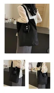 Detail of black canvas tote bag featuring a small detachable embroidered eye pouch