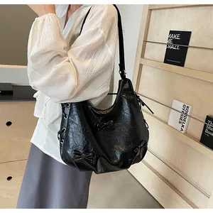 Close-up of black PU leather tote bag with bow details and silver eyelet drawstring
