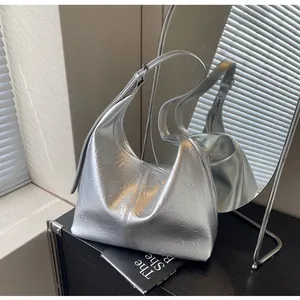 Reflet miroir montrant un sac fourre-tout argenté brillant avec bandoulière réglable