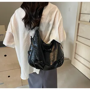 Detailed back view of a black pleated leather tote bag with stylish bows on a model