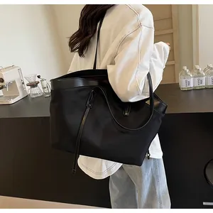 Detail of the large black tote bag showing leather straps and spacious design in use