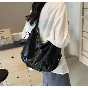 Detail of black faux leather tote with textured wrinkles and chic ribbon bow decoration