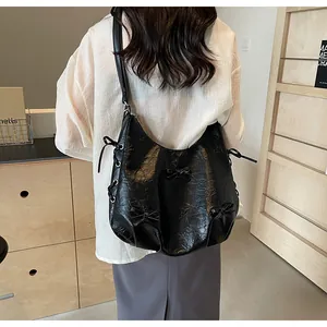 Rear view of a black ruffled leather tote bag with bow details and side straps on a model