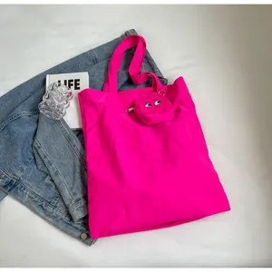 Hot pink foldable tote bag and embroidered monster eyes pouch set on denim jacket