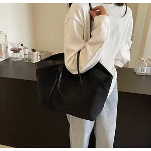 Detail of minimalist black tote bag with leather straps in a cafe setting