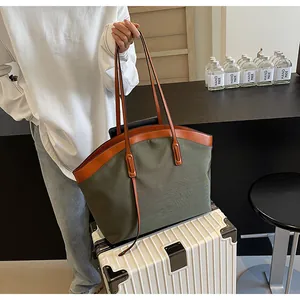 Detail of army green canvas tote bag with brown leather handles on white suitcase