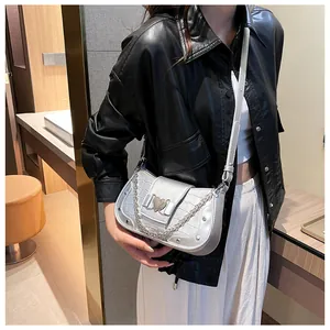 Detail of silver crocodile pattern bag with heart buckle and metal chain strap