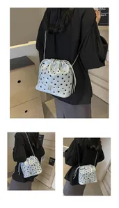 Détail du sac seau argenté avec découpes circulaires et bandoulière en chaîne fine