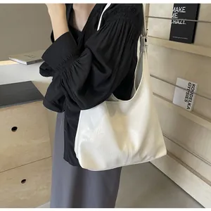 Détail du sac cabas en cuir blanc avec texture souple et boucle dorée sur la bandoulière