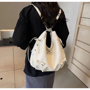 Detailed back view of cream white pleated leather backpack with bow accents