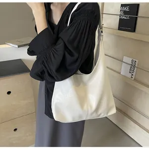 Détail d'un sac hobo blanc à texture plissée porté par un mannequin en décor doux