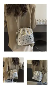 Détail du sac seau argenté avec anneaux métalliques évidés, chaîne et cordon de serrage