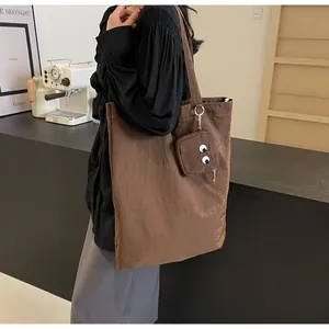 Detailed shot of brown textured tote bag featuring a cute cartoon eye coin purse charm