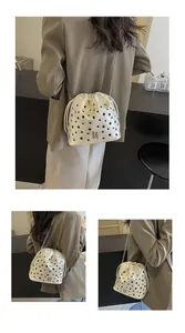 Vue détaillée du sac seau blanc avec cordon, œillets noirs et bandoulière en chaîne
