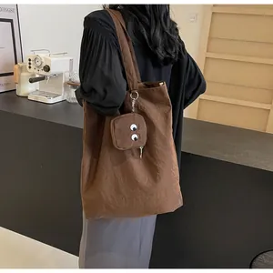 Detail of dark brown tote bag with cute monster embroidery coin purse on shoulder