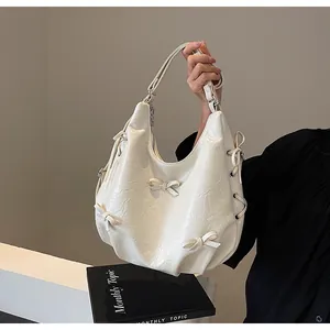 Close-up of cream pleated tote bag with 3D bow details and adjustable strap