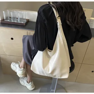 Détail d'un sac cabas plissé blanc avec boucle dorée et large bandoulière