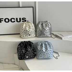 Sacs seaux texturés en crème, argent, noir et bleu avec détails d'oeillets métalliques
