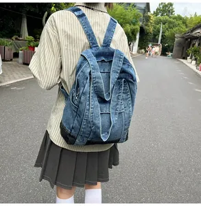 Rear view of model wearing a large blue washed denim backpack in a street setting