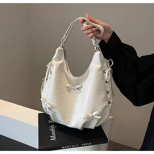 Close-up of white pleated hobo bag with delicate bow details and soft leather texture