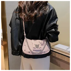 Detail of pink faux crocodile leather bag featuring a silver heart-shaped metal buckle