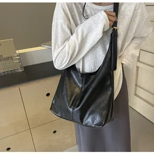 Détail du sac cabas noir avec texture en cuir plissé et boucle en métal doré