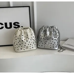 Détail des sacs seaux argent et blanc perle avec œillets métalliques et bandoulières chaîne