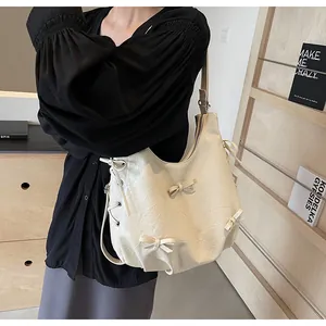 Detail of creamy white tote bag with ribbon bows and soft pleated texture texture on a model