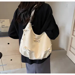 Detail of cream white PU leather tote bag with elegant ribbon bows and crinkled texture