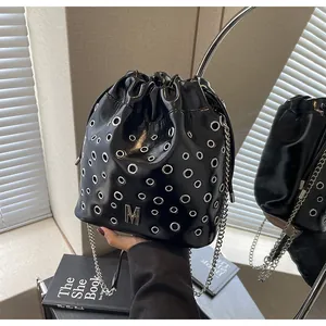 Détail du sac seau en cuir noir avec œillets métalliques argentés et bandoulière chaîne