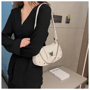 Detail of white crocodile pattern shoulder bag with silver heart buckle and metal chain