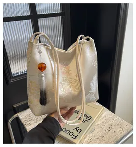 Detail of beige floral jacquard tote bag with elegant tassel charm and leather handle
