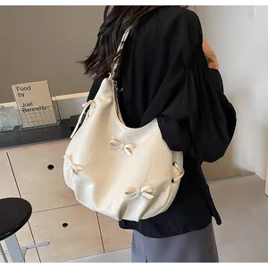 Detail of cream pleated tote bag with bow accents and glossy PU leather texture