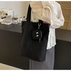Detail of black monster tote bag with white eye embroidery and matching small zipper pouch