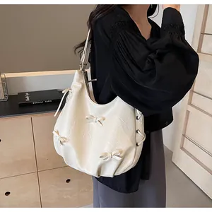 Detail of cream hobo bag featuring decorative bows and unique pleated faux leather texture