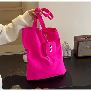 Detail of bright pink tote bag featuring a cute monster embroidered zipper coin purse pouch
