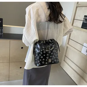Détail du sac seau noir à cordon avec œillets métalliques argentés et chaîne