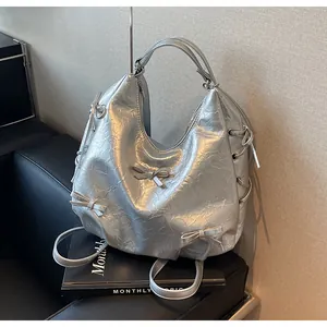 Detail of silver metallic hobo backpack with cute bows and eyelets on wrinkled faux leather