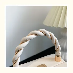 Détail de la poignée en cuir élégante avec chaîne en métal doré torsadée et coutures