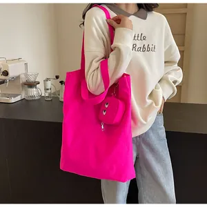 Detail of rose pink canvas tote bag with embroidered cartoon monster eye pendant