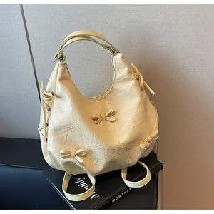 Close-up of creamy yellow pleated tote bag featuring 3D bowknot details and soft texture