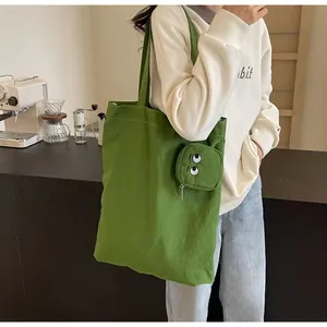 Detail of green canvas tote bag set with a mini monster eye embroidery coin purse charm