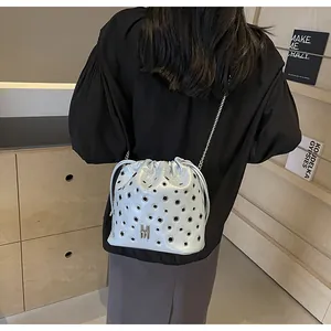 Détail du sac seau bleu clair avec œillets métalliques et bandoulière en chaîne